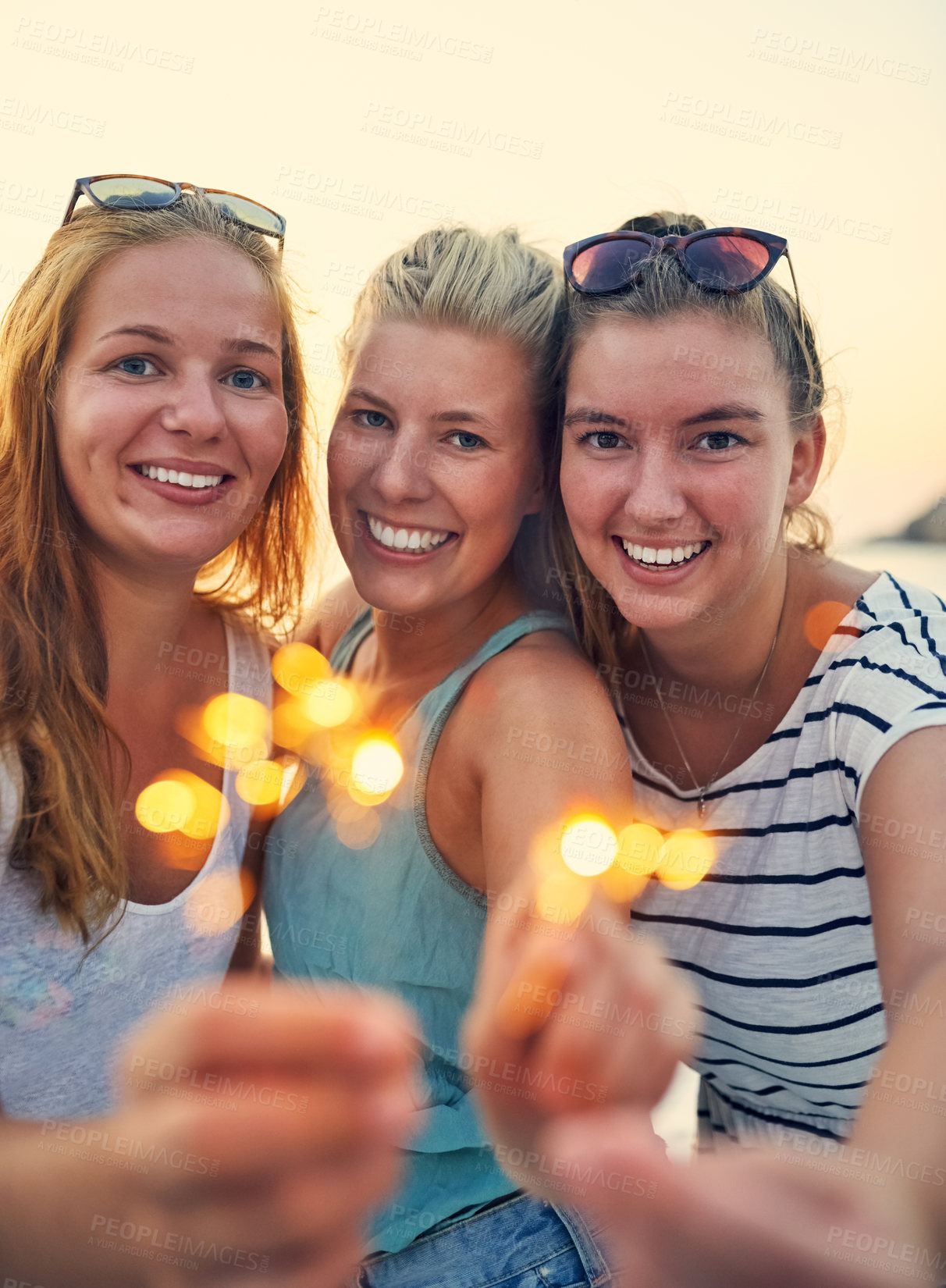 Buy stock photo Smile, sparklers and beach with friends portrait at sunset party for summer, vacation or holiday in nature together. New years, firework or celebration with women, bonding and drinking by Miami sea