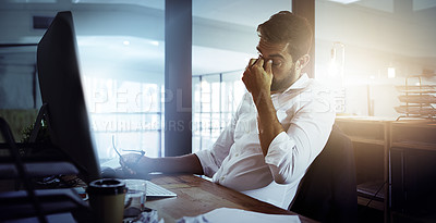 Buy stock photo Cropped shot of a young businessman looking stressed while working late in the office