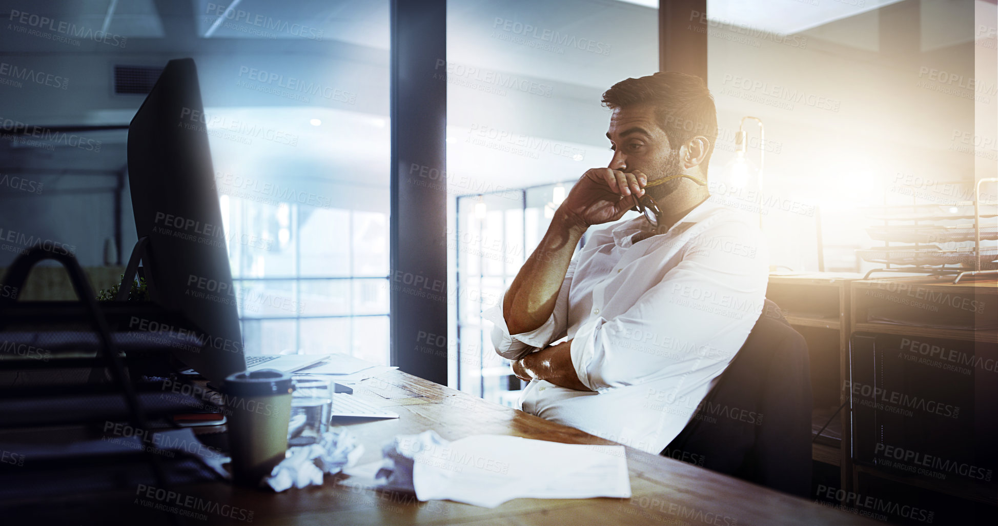 Buy stock photo Cropped shot of a handsome young businessman looking thoughtful while working late in the office