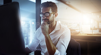 Buy stock photo Cropped shot of a handsome young businessman looking thoughtful while working late in the office