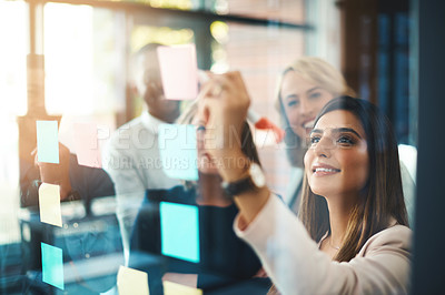 Buy stock photo Team leader planning and writing on sticky notes while showing innovation, sharing a vision and ideas. Diverse group of creative office business people meeting together to market new startup company