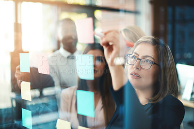 Buy stock photo Marketing leader planning and writing on sticky notes on wall while support and sharing vision or idea. Diverse group of creative office business people meeting together to market new startup company