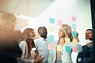 Buy stock photo Shot of a group of businesspeople arranging sticky notes on a glass wall in a modern office