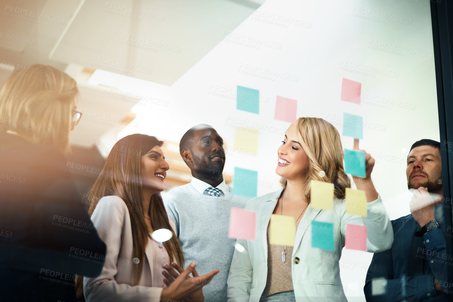 Buy stock photo Shot of a group of businesspeople arranging sticky notes on a glass wall in a modern office