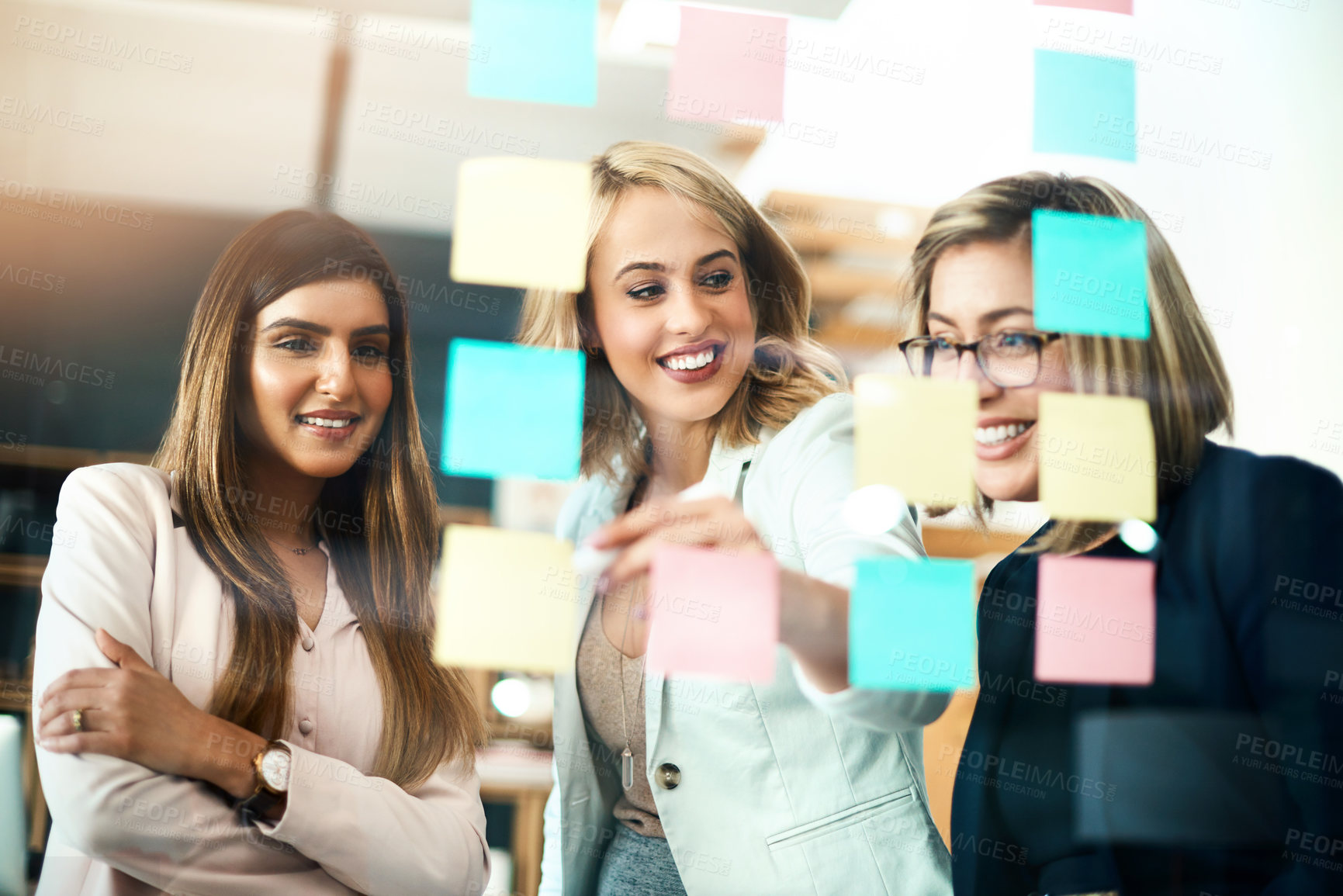 Buy stock photo Female leader, team manager and boss planning with her colleagues on a glass wall using sticky notes. Strategy, mission and vision for a small business startup in the office boardroom for growth