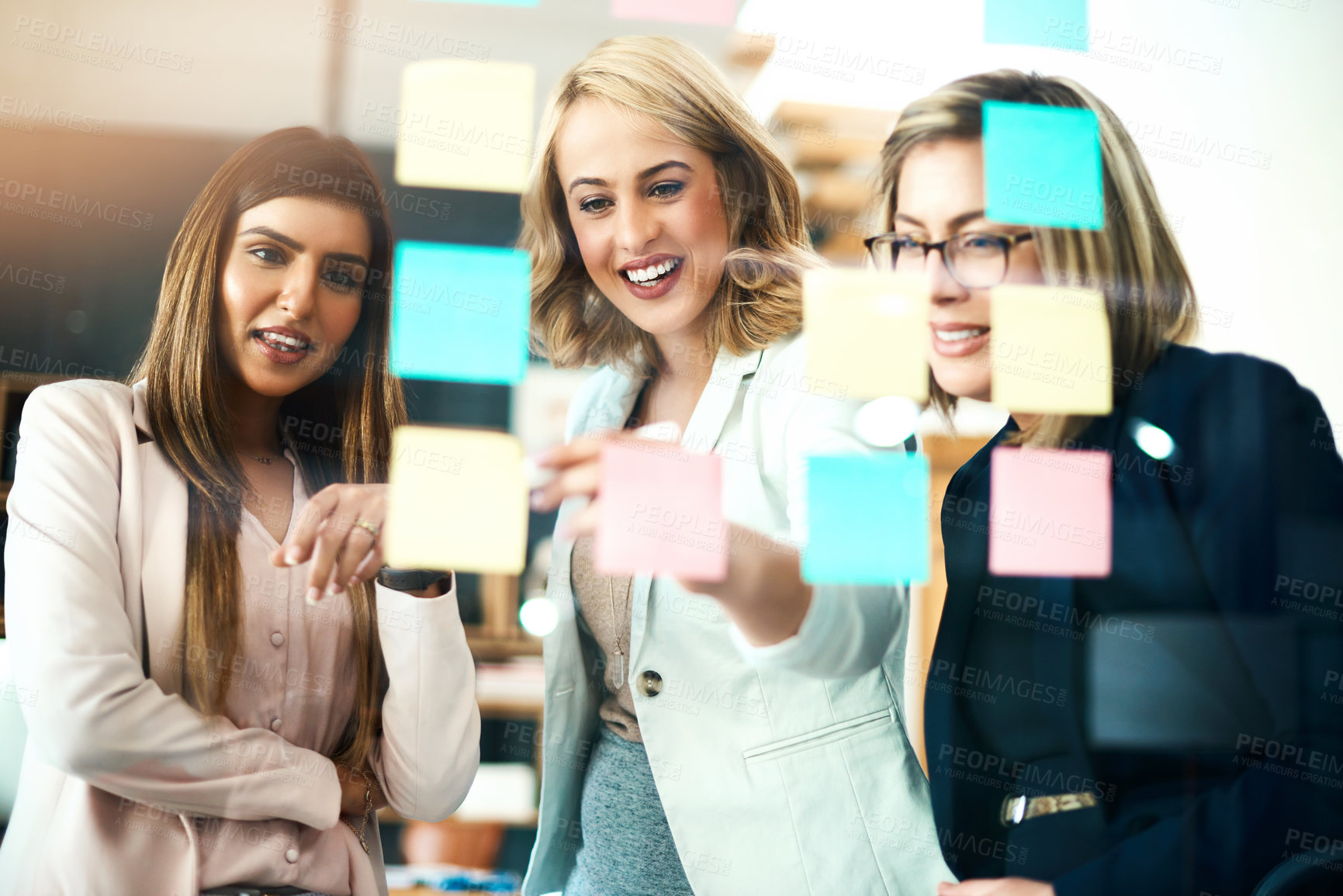 Buy stock photo Business women, brainstorming and planning schedule of target, team goals and agenda at window. Happy employees, diversity and sticky note for timeline of workflow process, calendar and project ideas