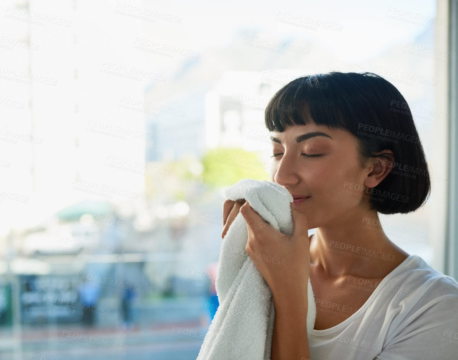 Buy stock photo Cropped shot of a young woman smelling freshly washed towels at home
