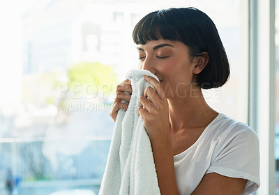 Buy stock photo Cropped shot of a young woman smelling freshly washed towels at home