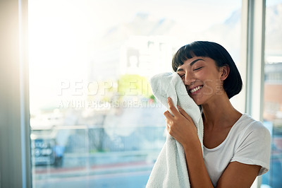 Buy stock photo Cropped shot of a young woman rubbing a freshly washed towel against her face