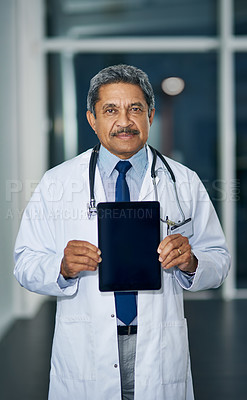 Buy stock photo Portrait of a mature doctor holding up a digital tablet with a blank screen in a hospital