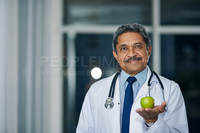 Buy stock photo Portrait of a mature doctor holding a green apple in a hospital