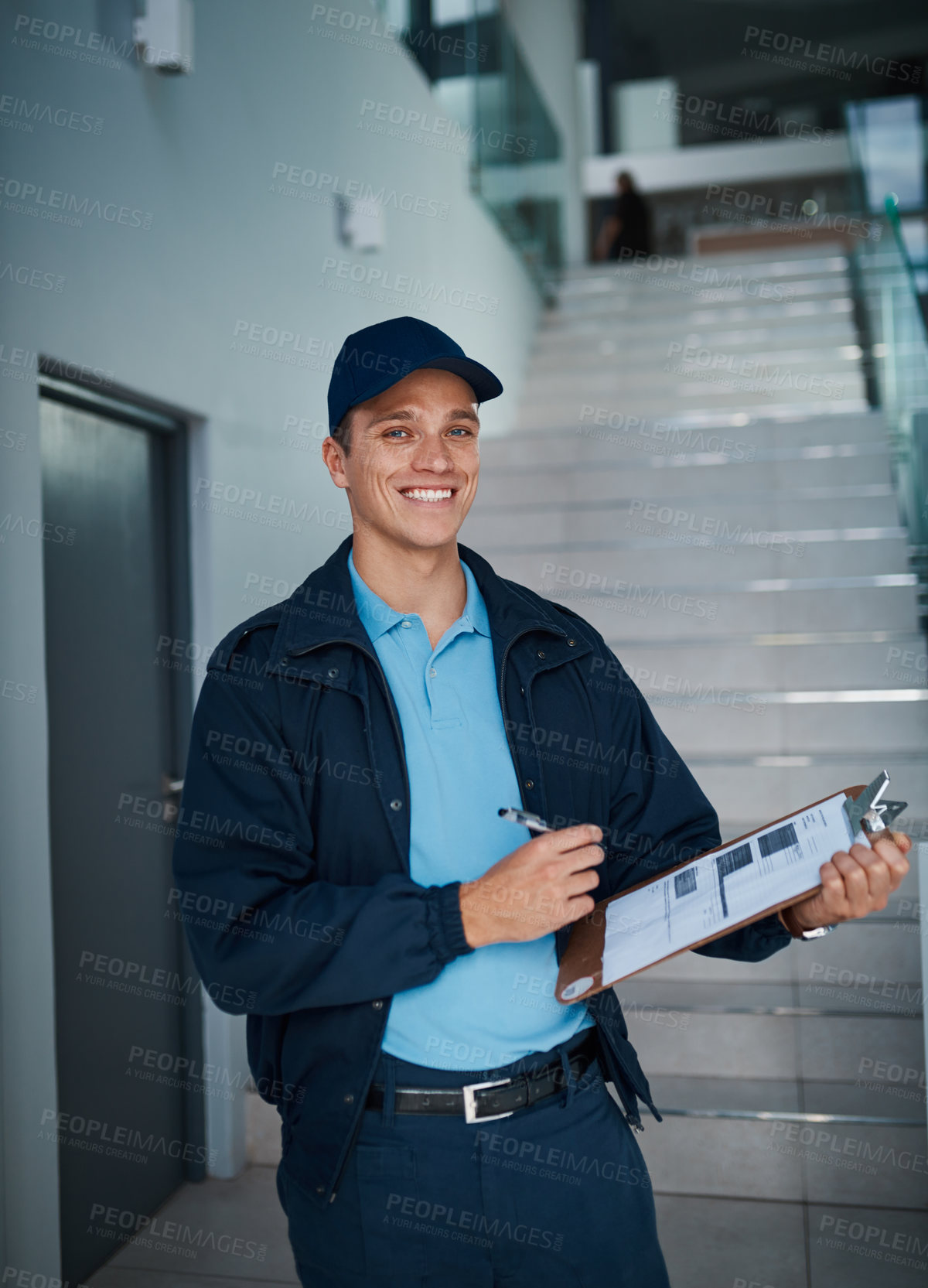 Buy stock photo Cropped shot of a handsome young man marking off his checklist on a clipboard indoors