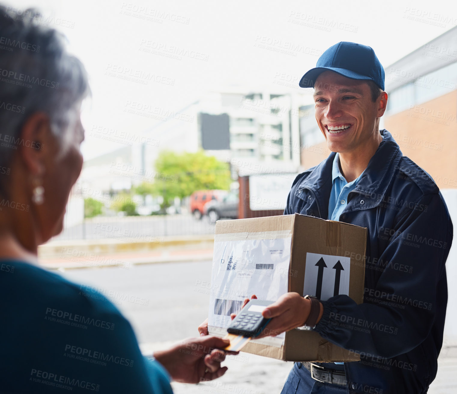 Buy stock photo Cropped shot of a handsome young man delivering a package to a customer and receiving payment with a card