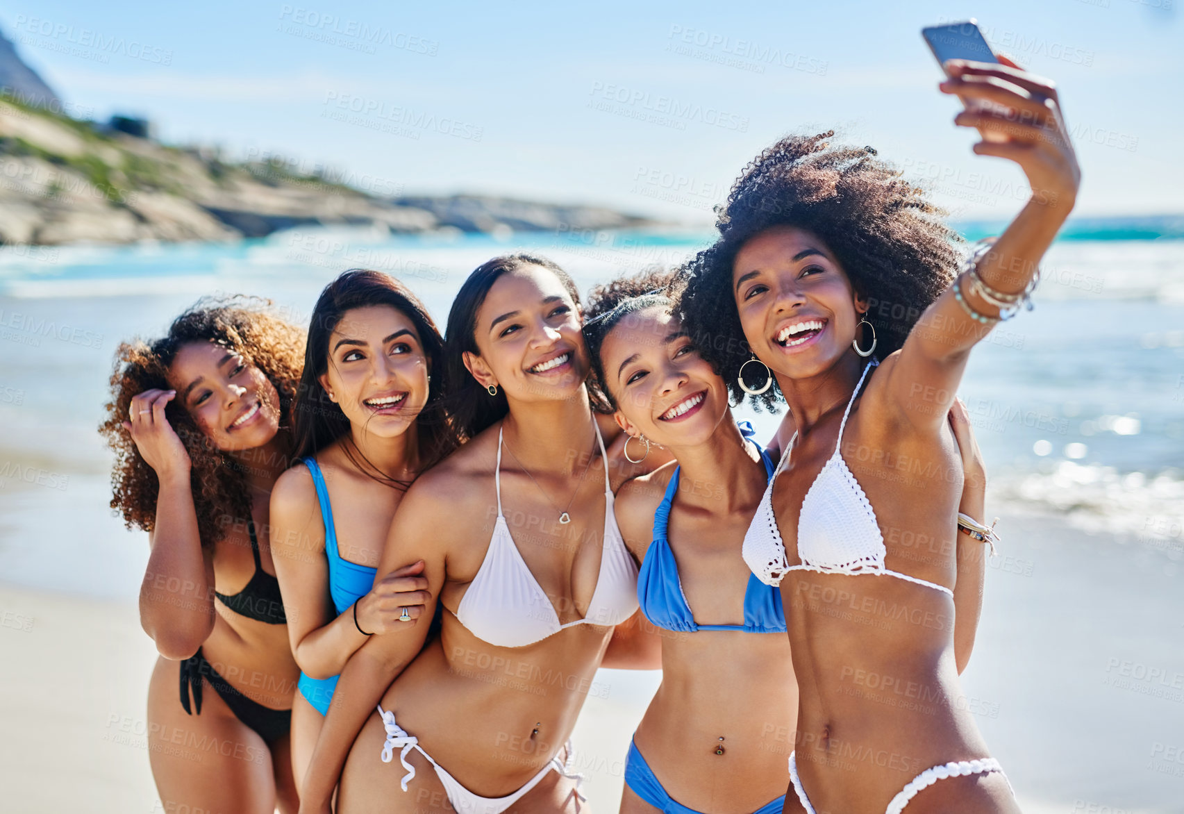 Buy stock photo Shot of a group of happy young women taking selfies together at the beach