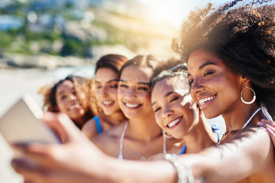 Buy stock photo Shot of a group of happy young women taking selfies together at the beach