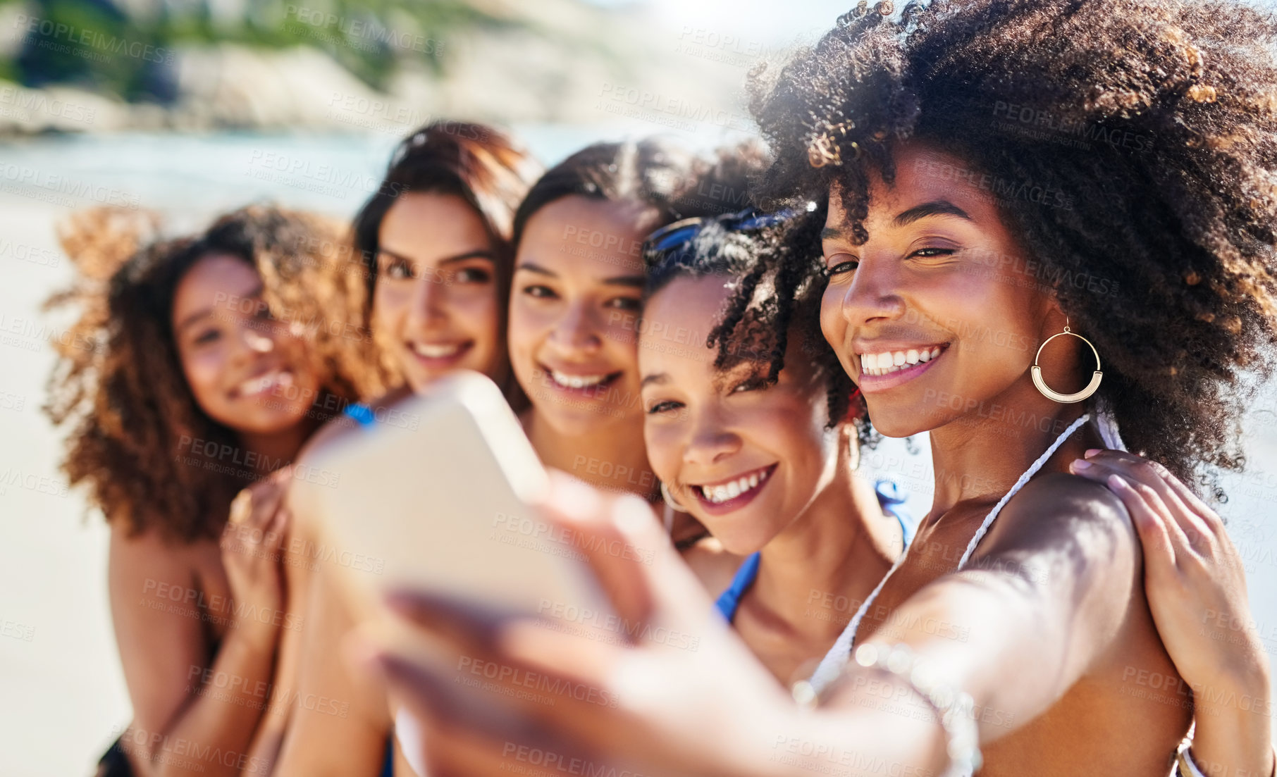 Buy stock photo Shot of a group of happy young women taking selfies together at the beach