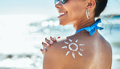 Buy stock photo Shot of a beautiful young woman with a sun drawn on her shoulder with sunscreen at the beach