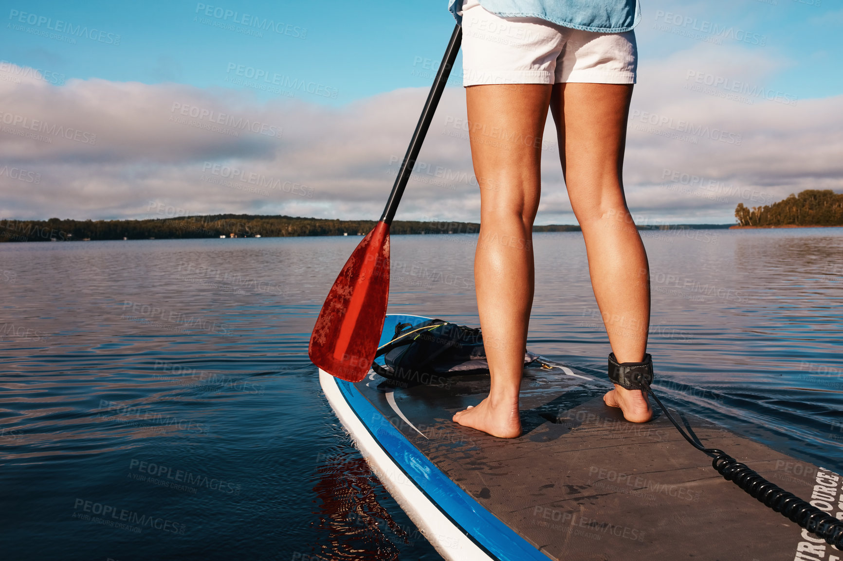 Buy stock photo Cropped shot of an unrecognizable woman paddle boarding on a lake