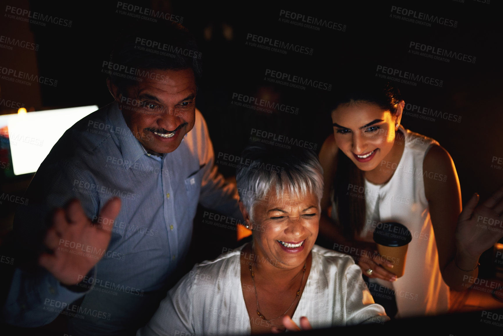 Buy stock photo Shot of a group of colleagues waving while making a video call on a computer at night in an office