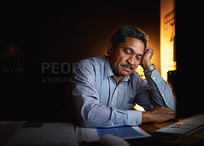 Buy stock photo Shot of a mature businessman sleeping at his desk while working late in an office