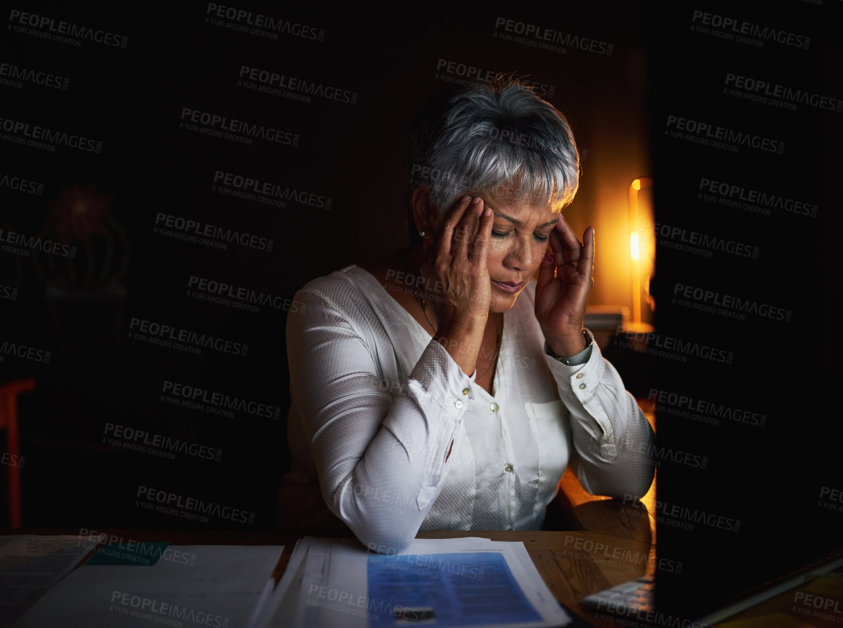 Buy stock photo Shot of a mature businesswoman looking stressed out while working late in an office
