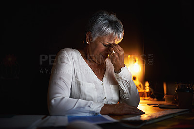 Buy stock photo Shot of a mature businesswoman looking stressed out while working late in an office