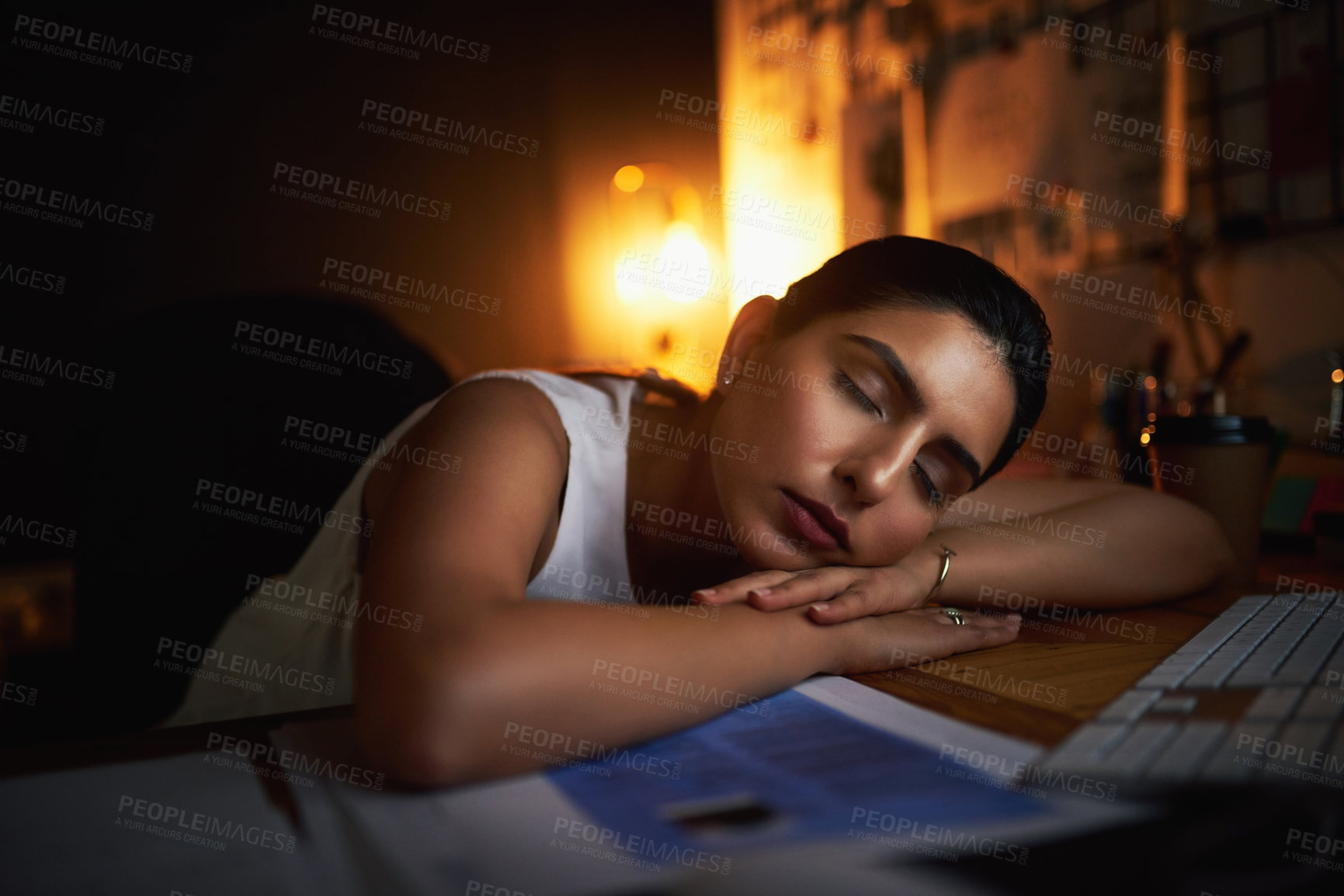 Buy stock photo Shot of a young businesswoman sleeping at her desk while working late in an office