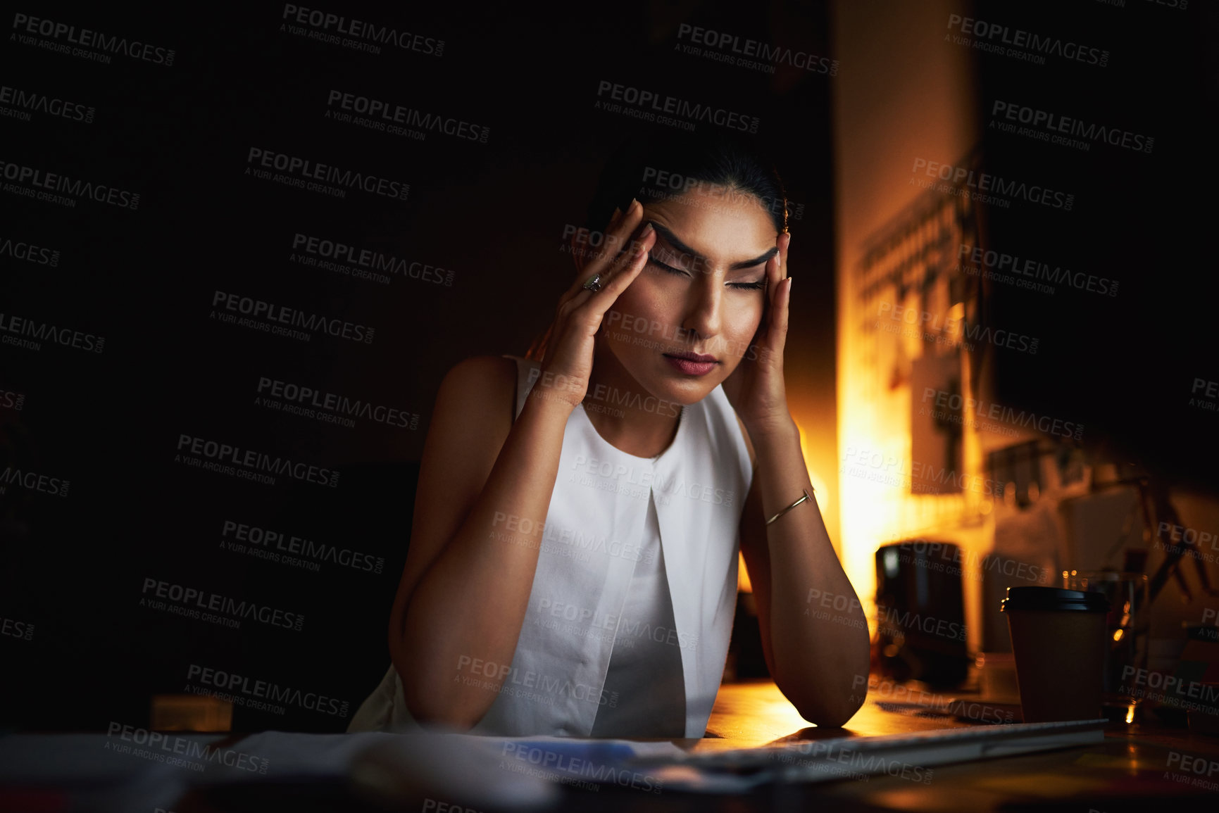Buy stock photo Shot of a young businesswoman looking stressed out while working late in an office
