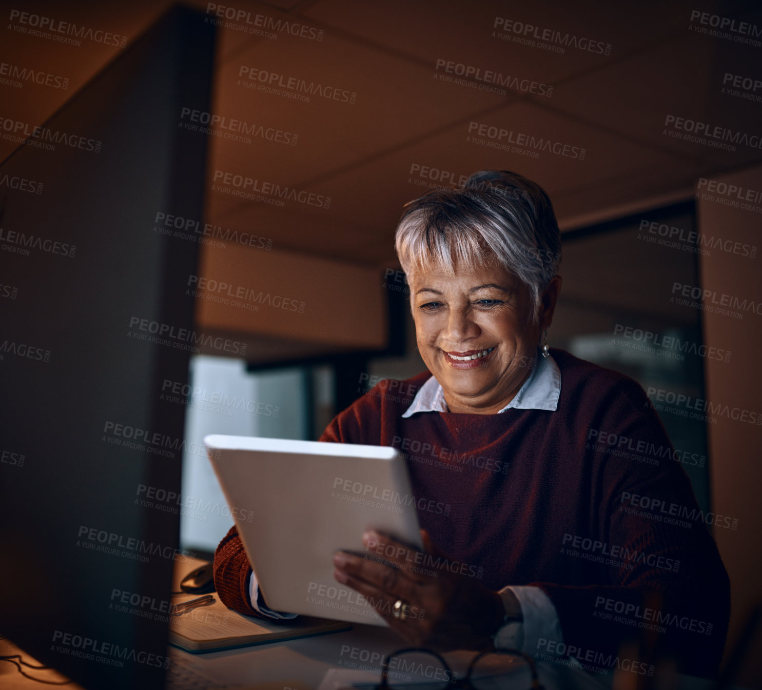 Buy stock photo Shot of a mature businesswoman using a digital tablet while working late in an office