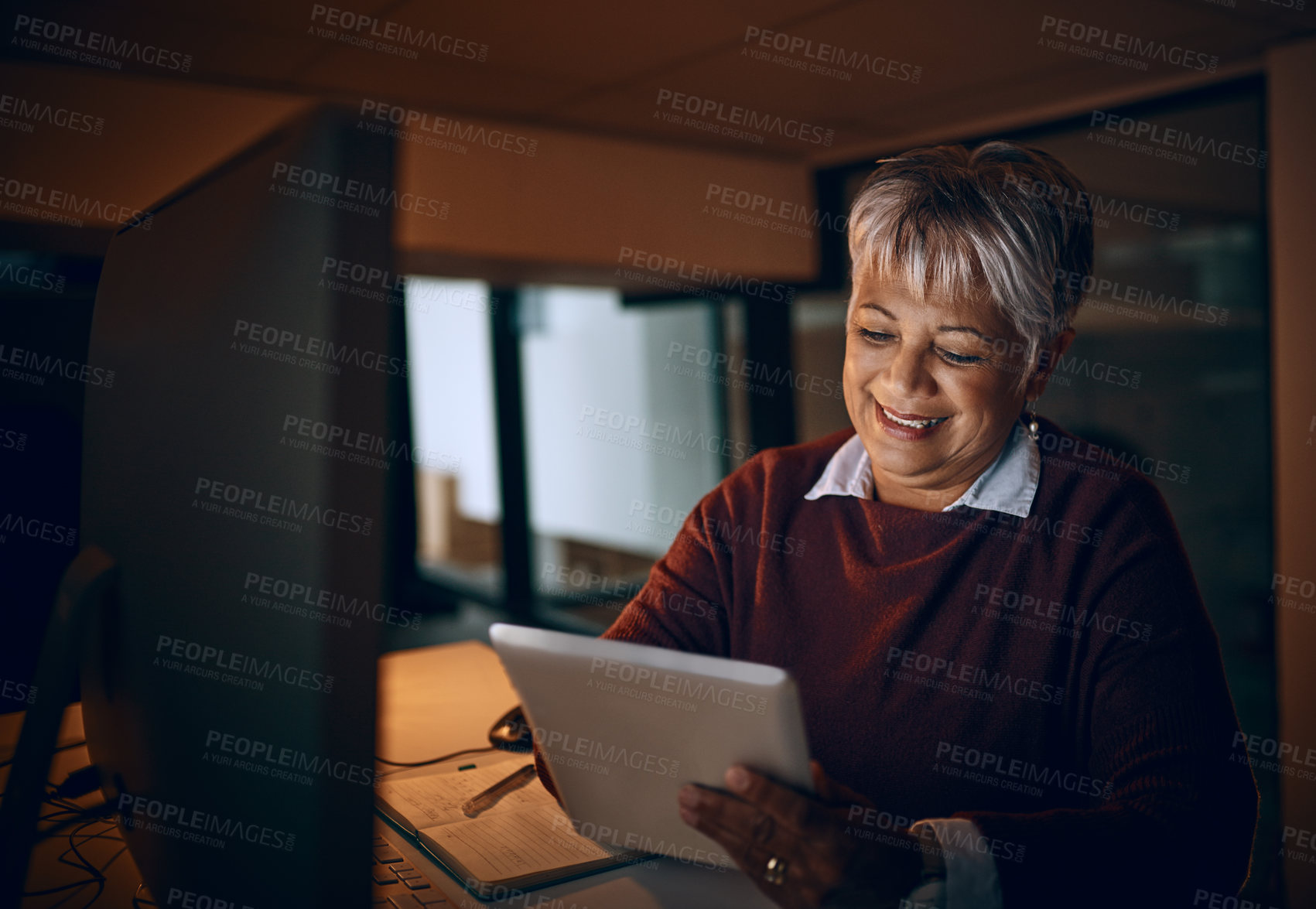 Buy stock photo Shot of a mature businesswoman using a digital tablet while working late in an office