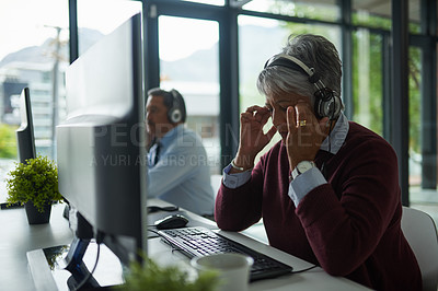 Buy stock photo Shot of a mature woman looking stressed out while working on a computer in a call centre