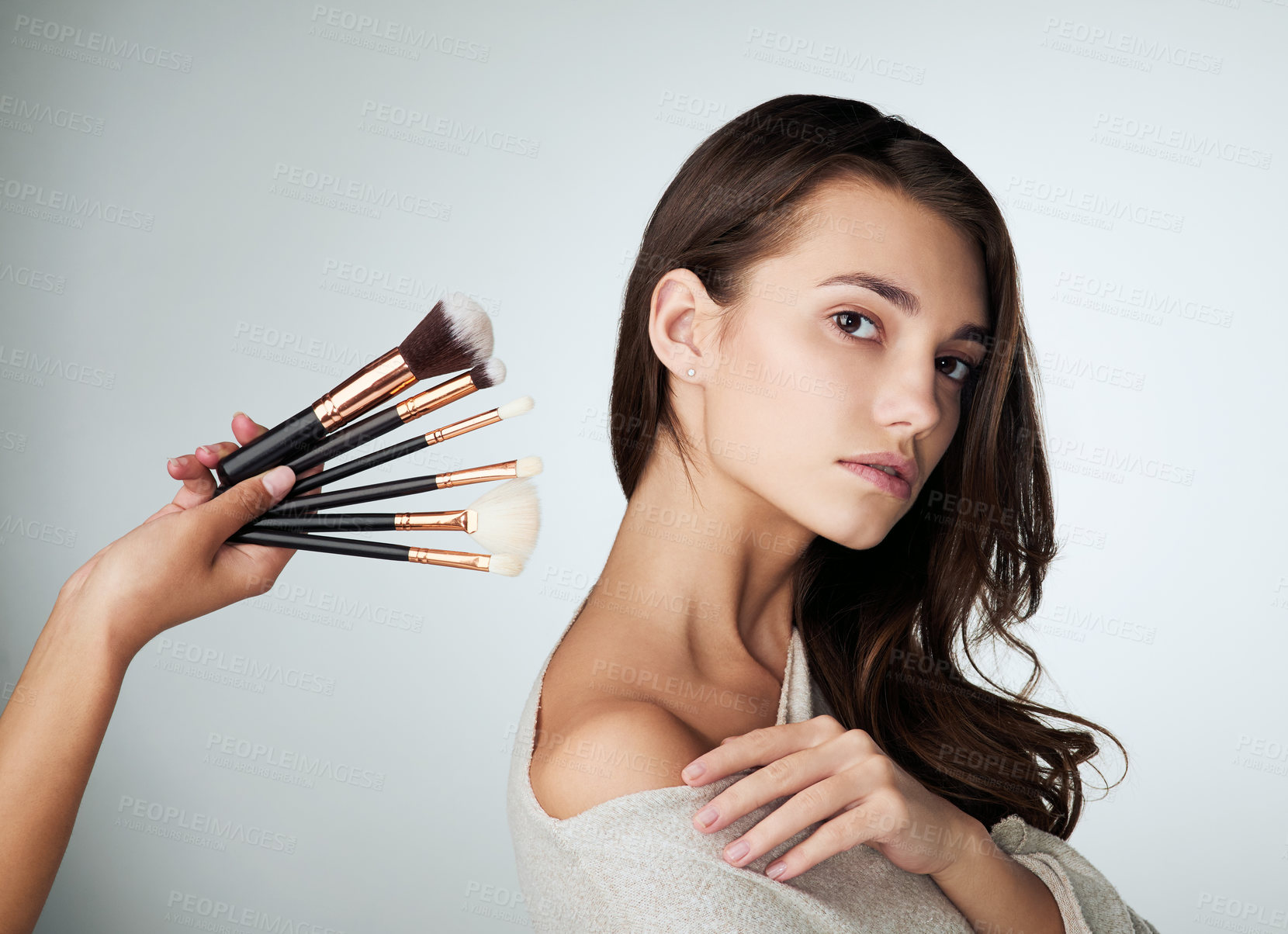 Buy stock photo Makeup, face brush and beauty of a woman in studio with natural glow on skin. Portrait of female person on a grey background with a hand for cosmetology tools, powder cosmetics and facial dermatology