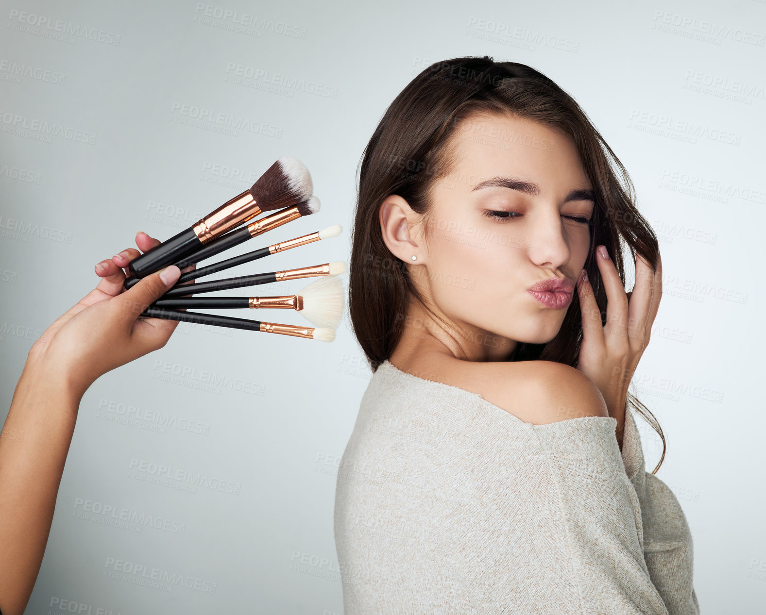 Buy stock photo Face, makeup brush and beauty of a woman in studio with a natural glow and shine. Headshot of a female person on a grey background with a hand and lips for cosmetology, facial cosmetics and skin care