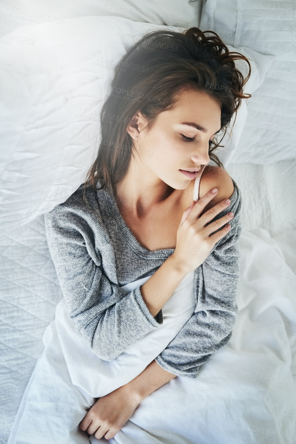 Buy stock photo Shot of an attractive young woman lying in bed with her eyes closed at home during the day