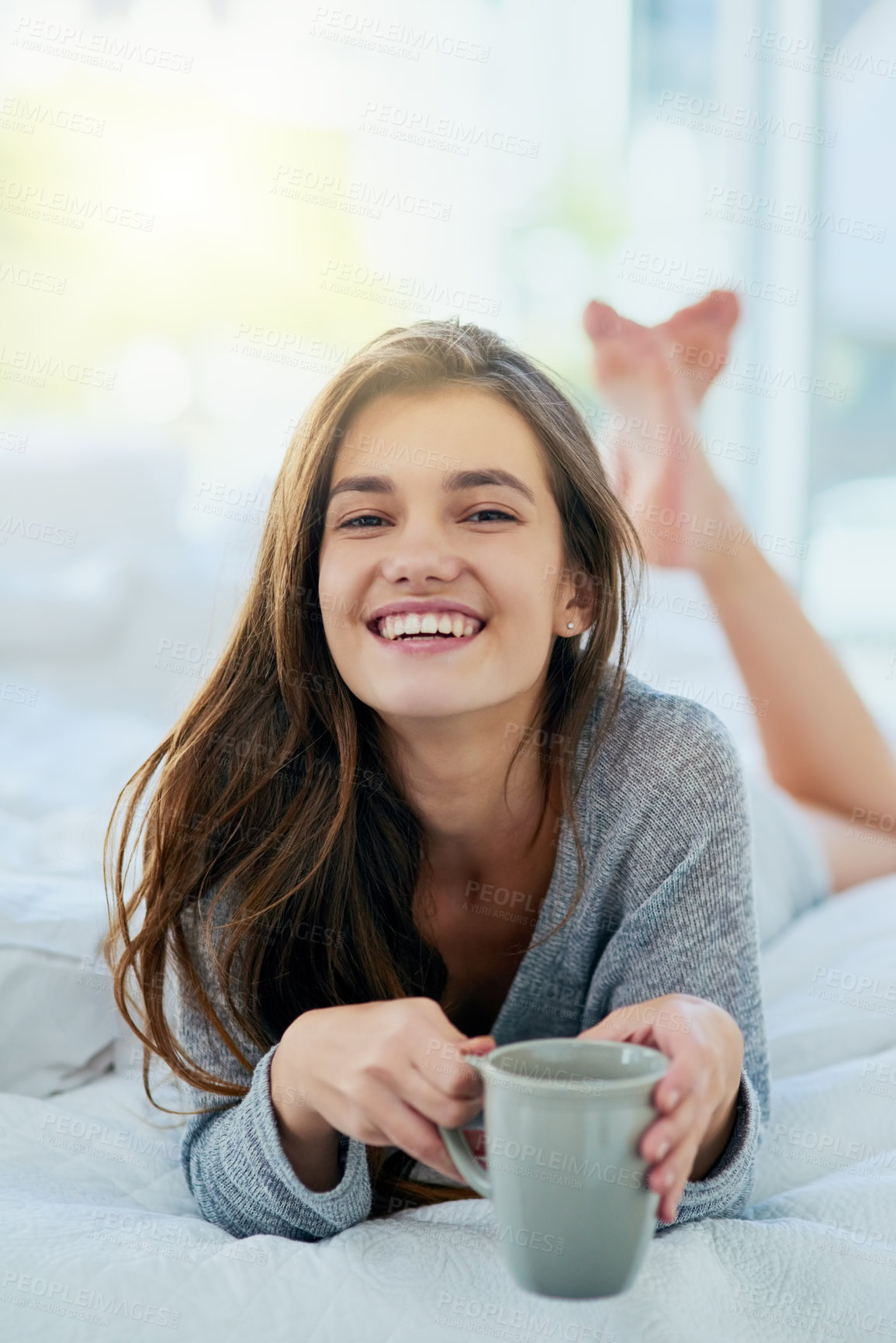 Buy stock photo Portrait of an attractive young woman drinking coffee while lying on her bed at home during the day