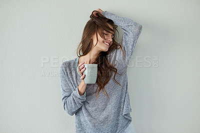 Buy stock photo Studio shot of an attractive young woman with her arm raised while drinking coffee against a white background