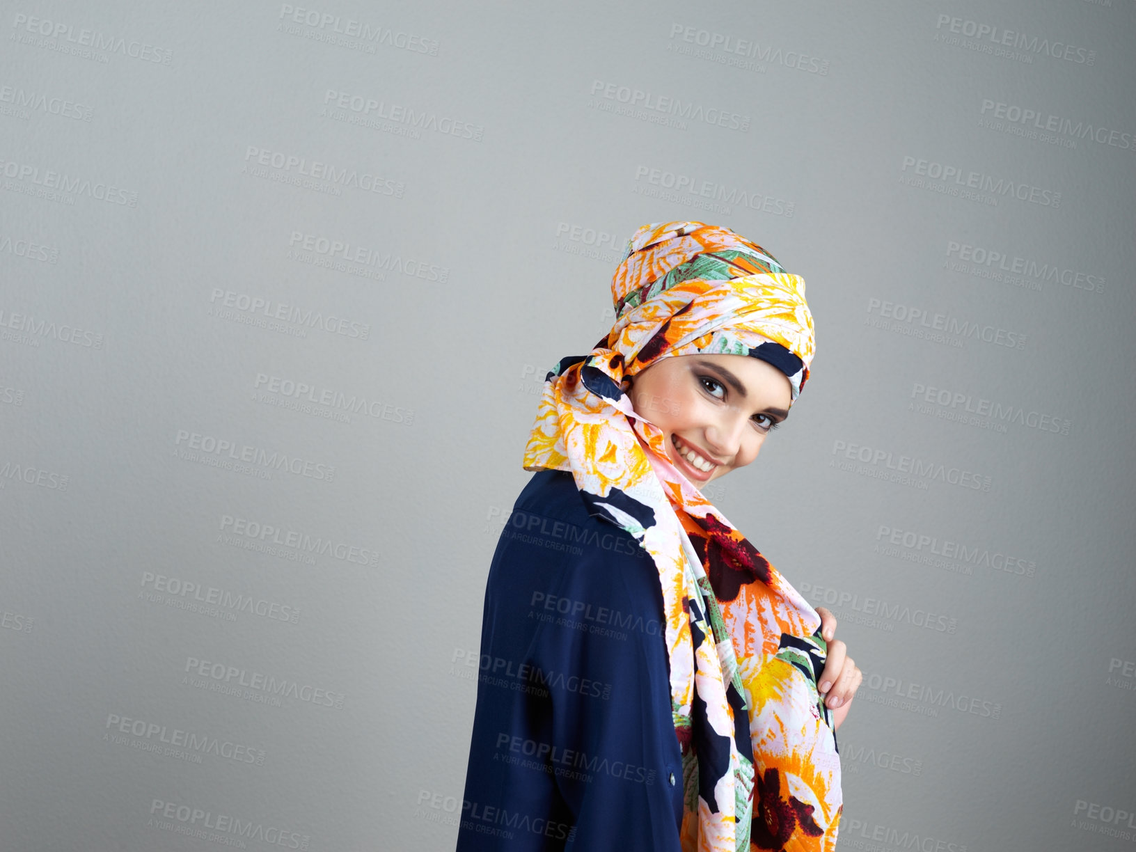 Buy stock photo Studio portrait of a confident young woman wearing a colorful head scarf while posing against a grey background