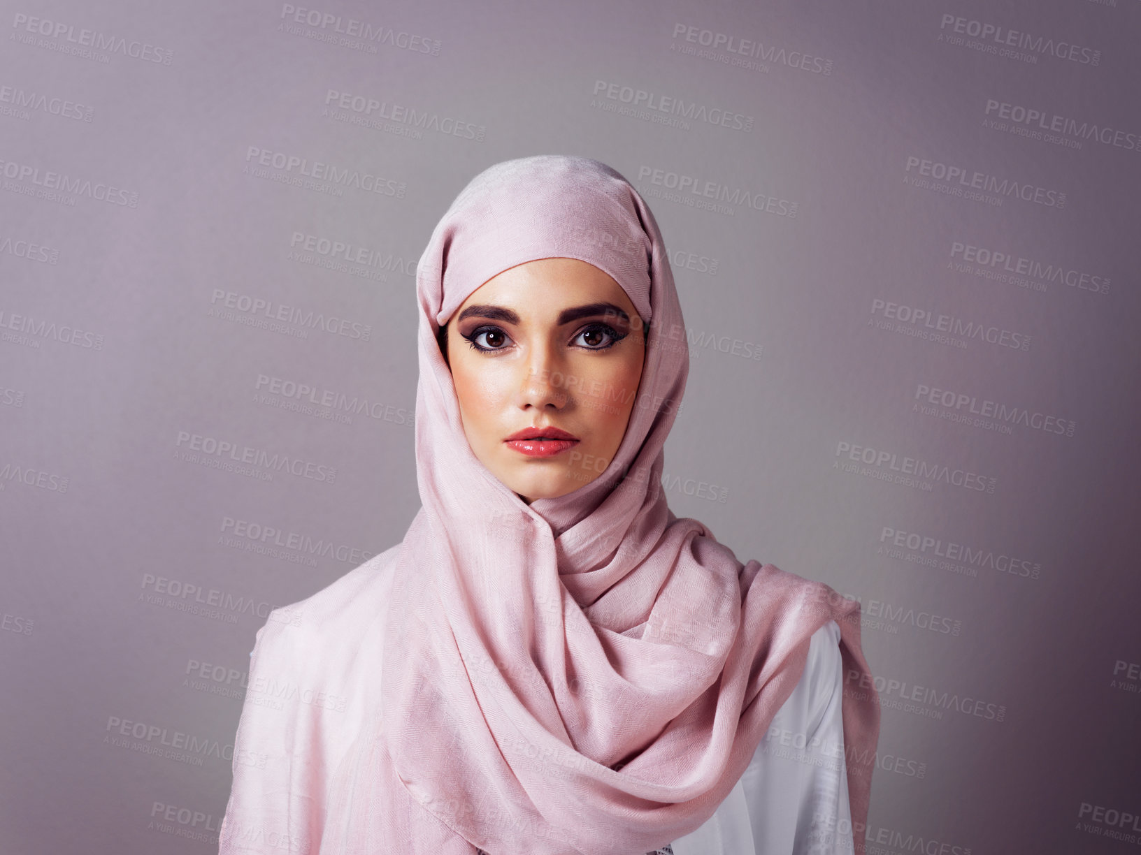 Buy stock photo Studio portrait of a cheerful young woman wearing a colorful head scarf while posing against a grey background