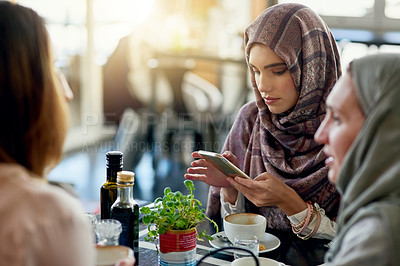 Buy stock photo Friends, phone and Muslim women in cafe, bonding and talking together. Coffee shop, cellphone and Islamic girls, group or people relax, conversation and discussion for social meeting in restaurant.