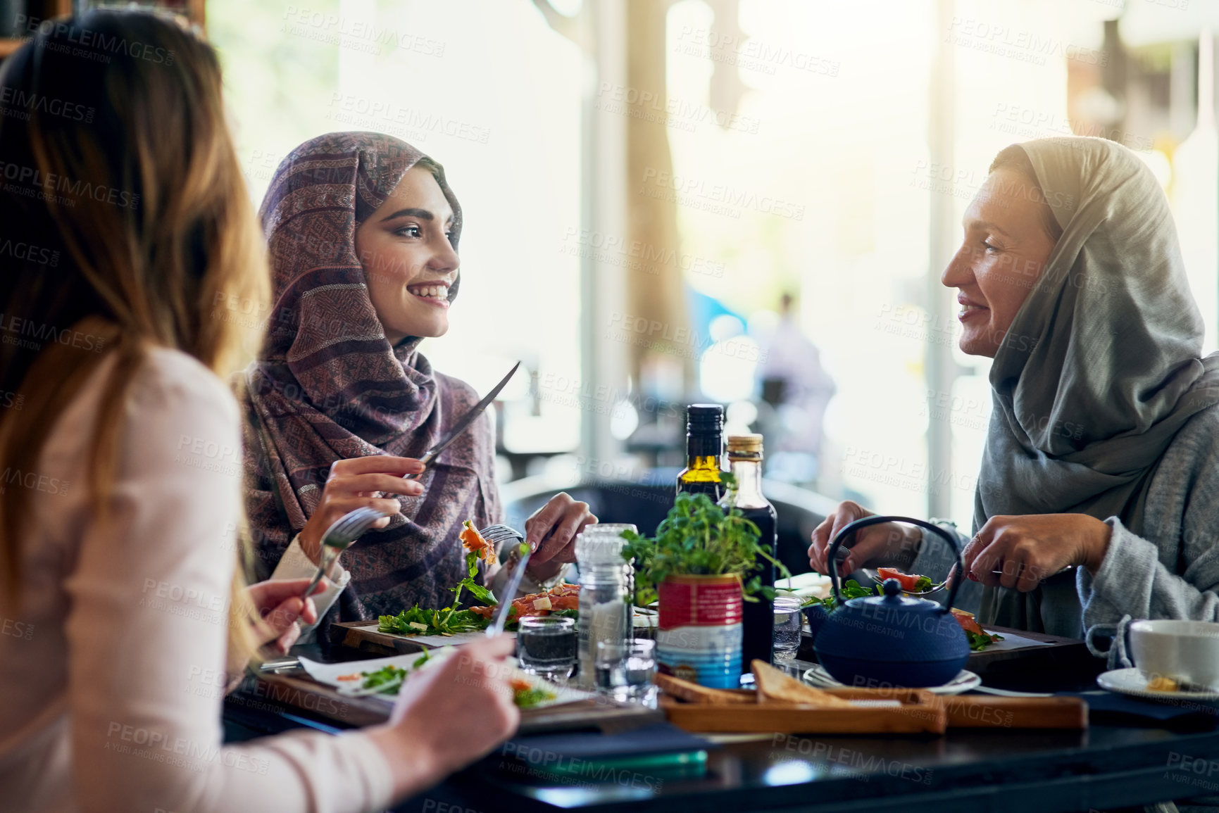 Buy stock photo Muslim women, friends and lunch in restaurant, together and talking with food, smile and happiness. Islamic woman, group and eating brunch with conversation, happy face and listen with food in cafe