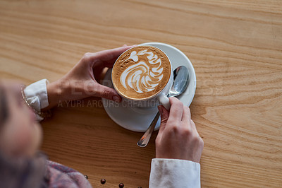 Buy stock photo High angle shot of a woman holding a cup of coffee decorated with froth art