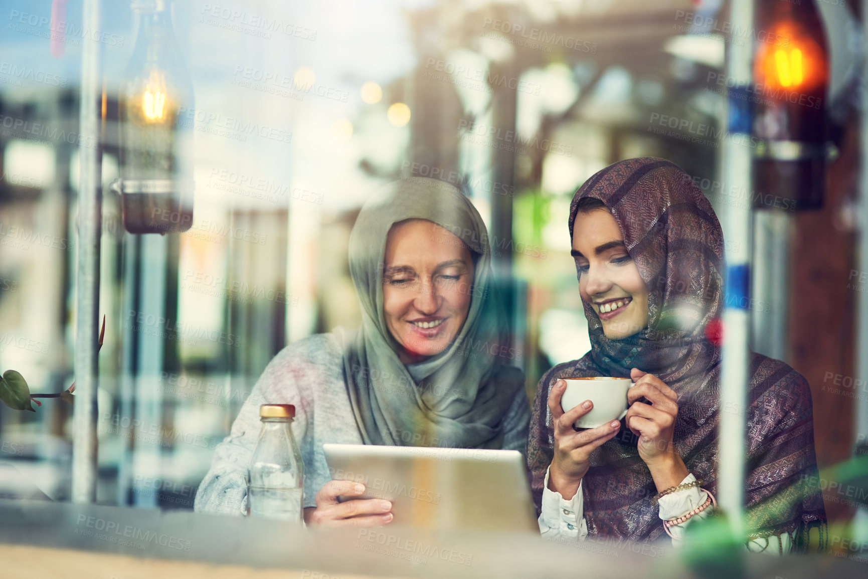Buy stock photo Shot of two women using a digital tablet together in a cafe
