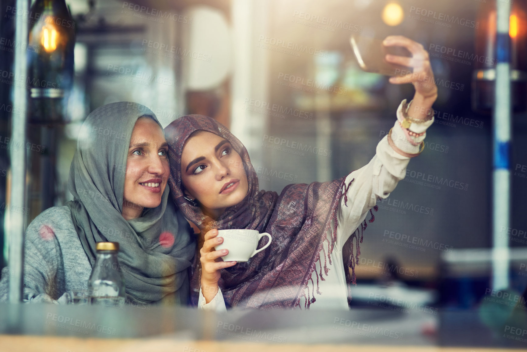 Buy stock photo Shot of two women taking selfies with a mobile phone in a cafe