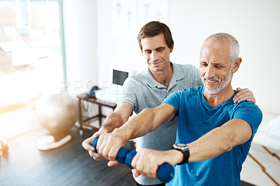 Buy stock photo Shot of a young male physiotherapist helping a client with stretching exercises in his office during the day