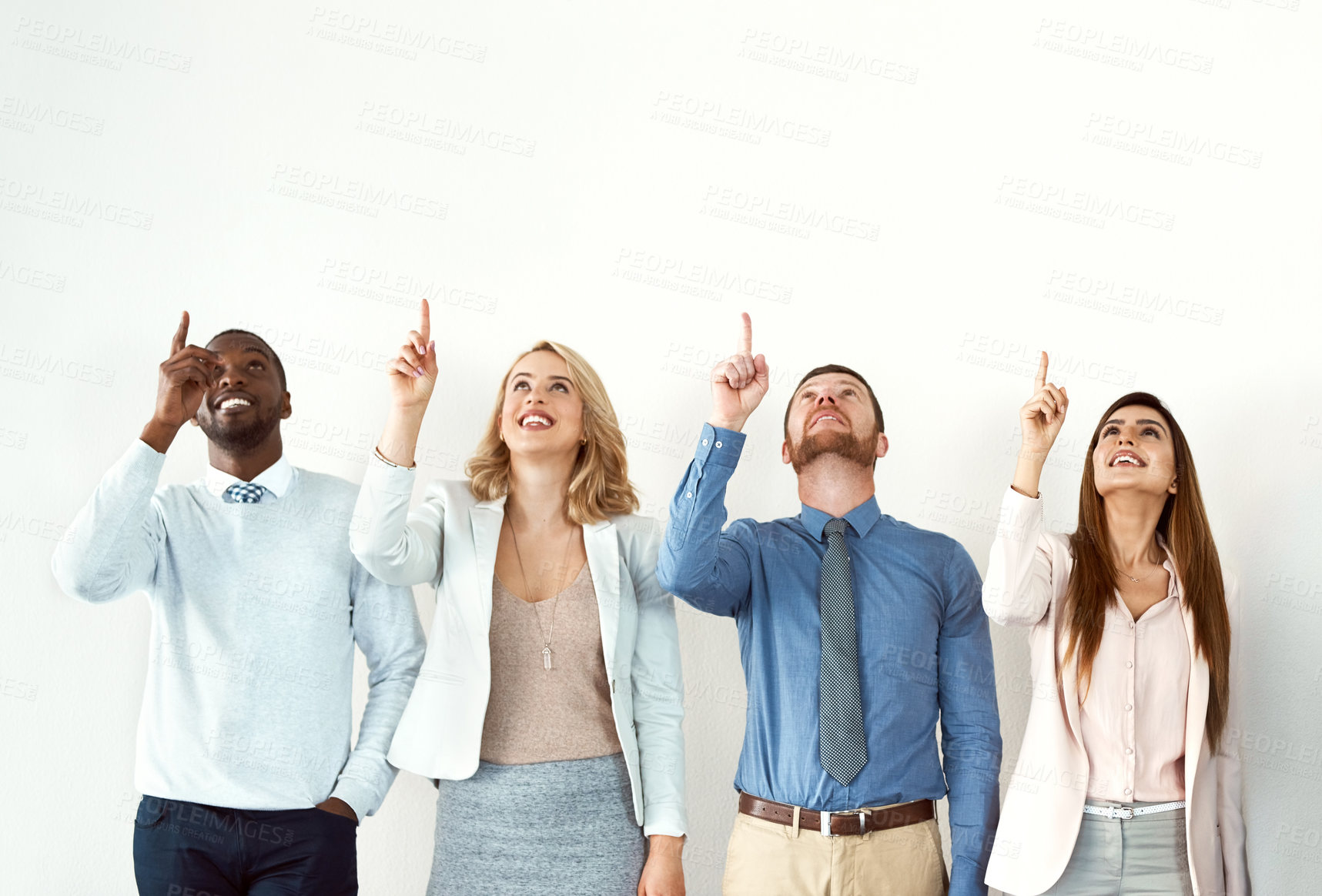 Buy stock photo Shot of a group of work colleagues looking up and pointing towards the sky while standing against a white background