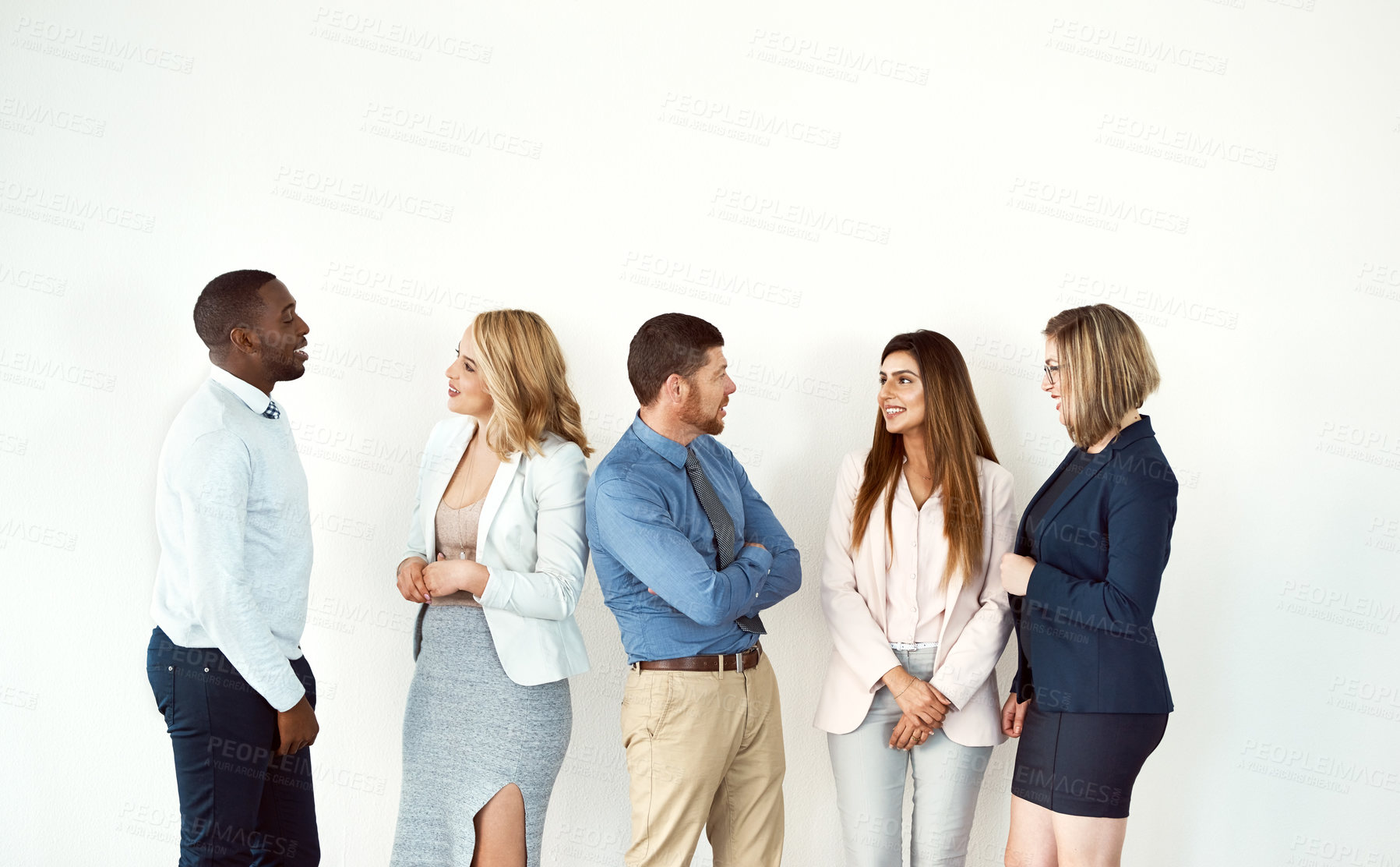 Buy stock photo Studio shot of a group of confident work colleagues standing and looking a each other against a white background