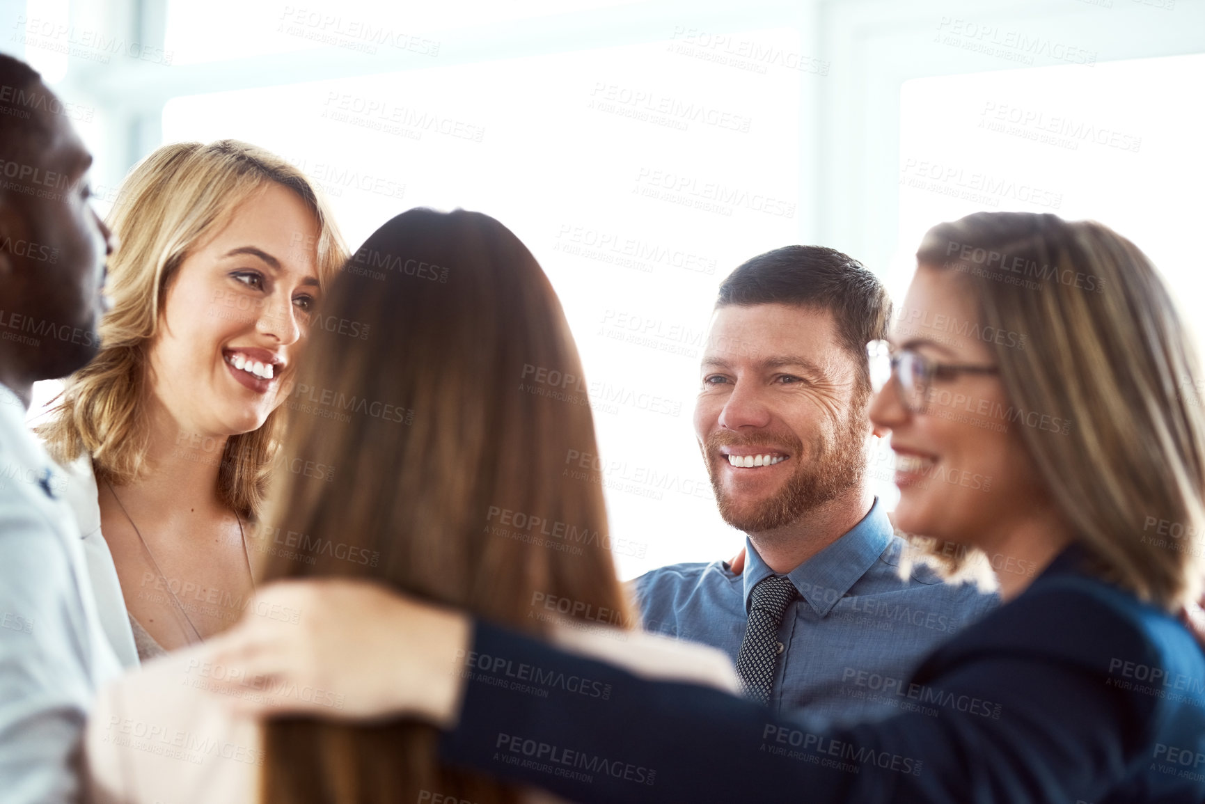 Buy stock photo Shot of a group of work colleagues forming a huddle together while standing in the office during the day