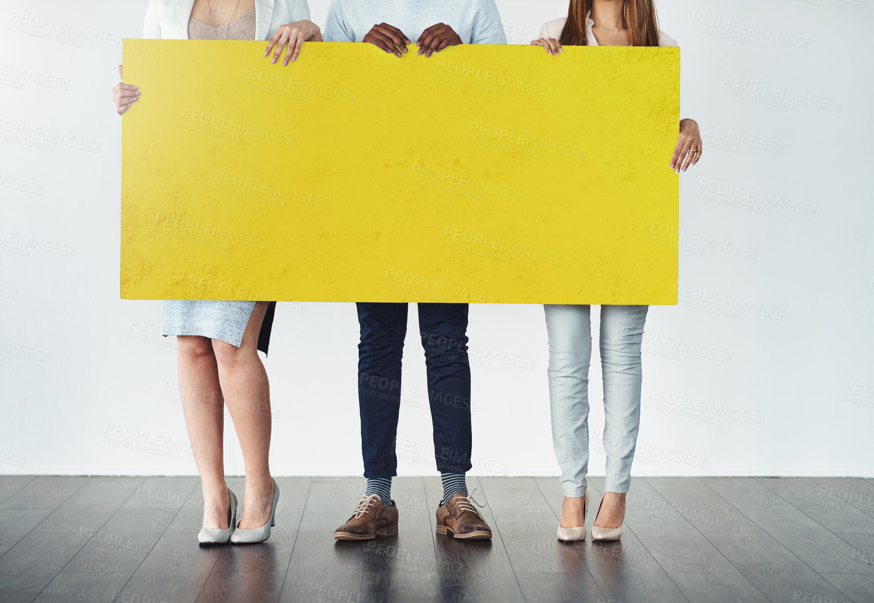 Buy stock photo Cropped studio shot of a group of businesspeople holding up a blank yellow placard