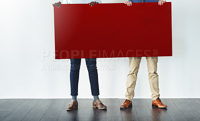Buy stock photo Cropped studio shot of two businessmen holding up a blank red placard