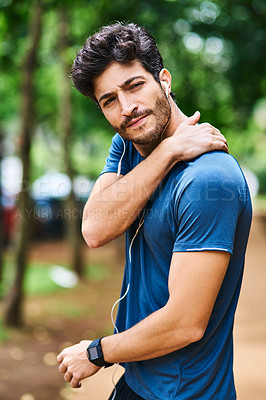 Buy stock photo Shot of a sporty young man holding his shoulder in pain while exercising outdoors